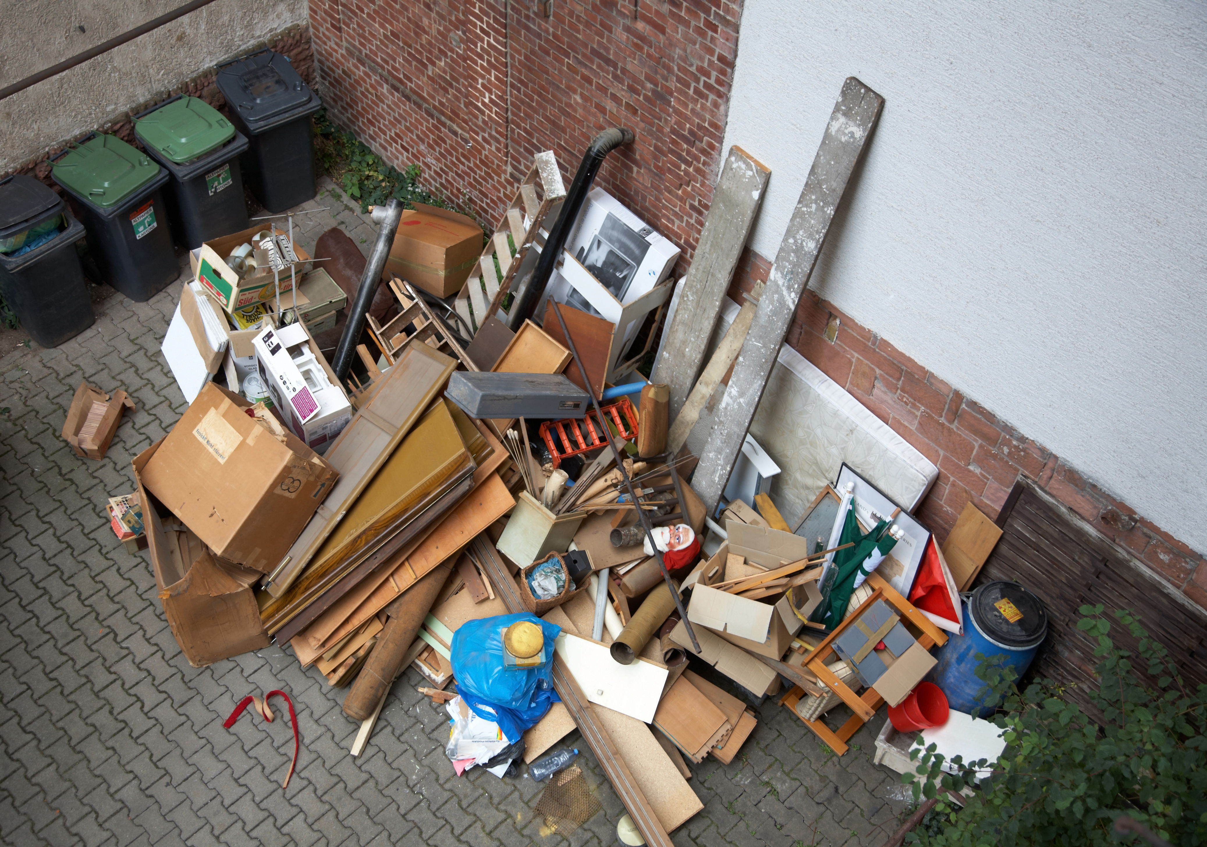 Kellerentrümpelung und Garagenauflösung mit fachgerechter Entsorgung von Möbeln, Sperrmüll und alten Materialien vor einem Wohnhaus.