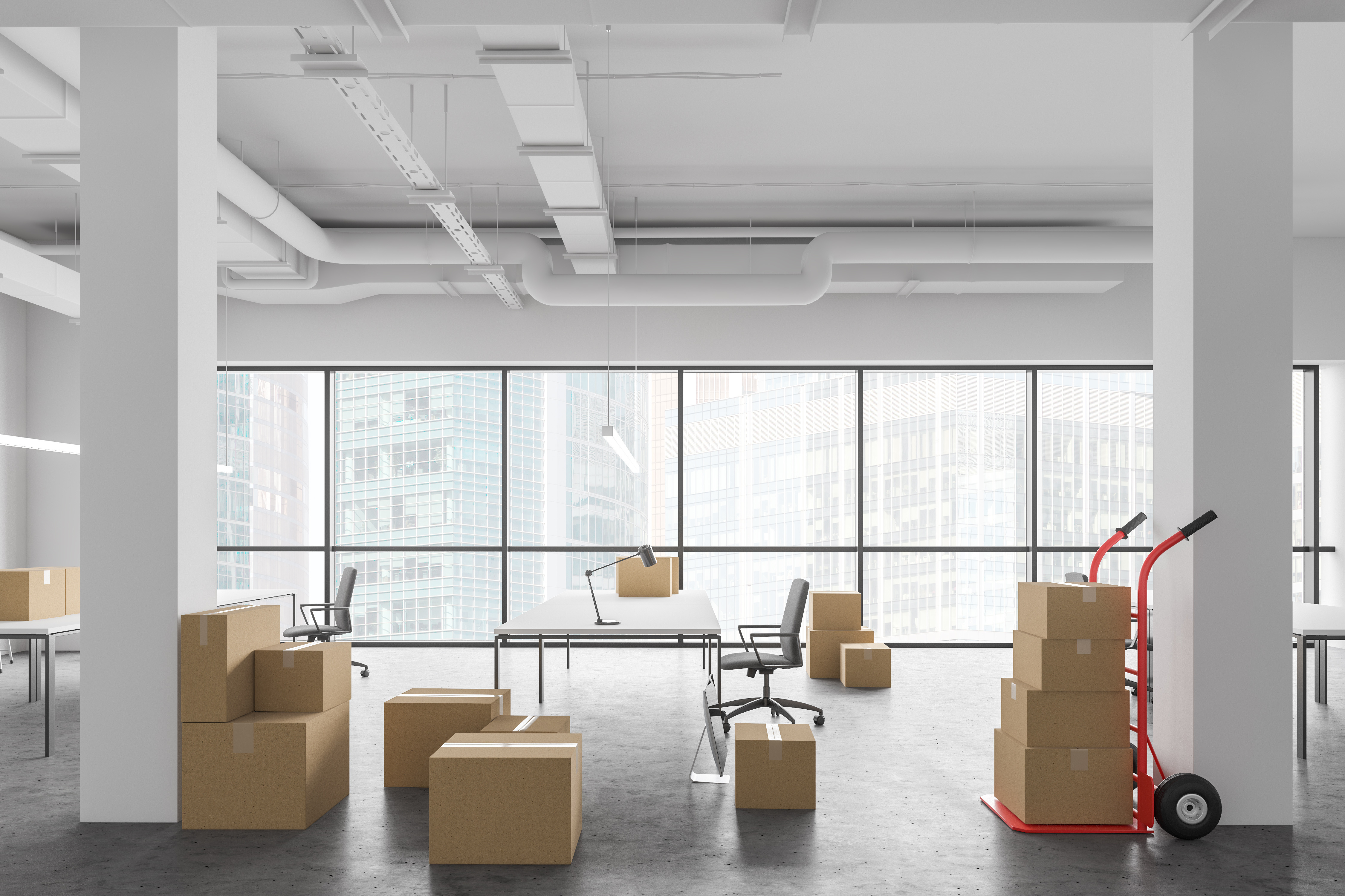 Modernes Büro mit Umzugskartons, leeren Schreibtischen und Transportwagen – Symbol für Firmenauflösung und Büroentrümpelung.