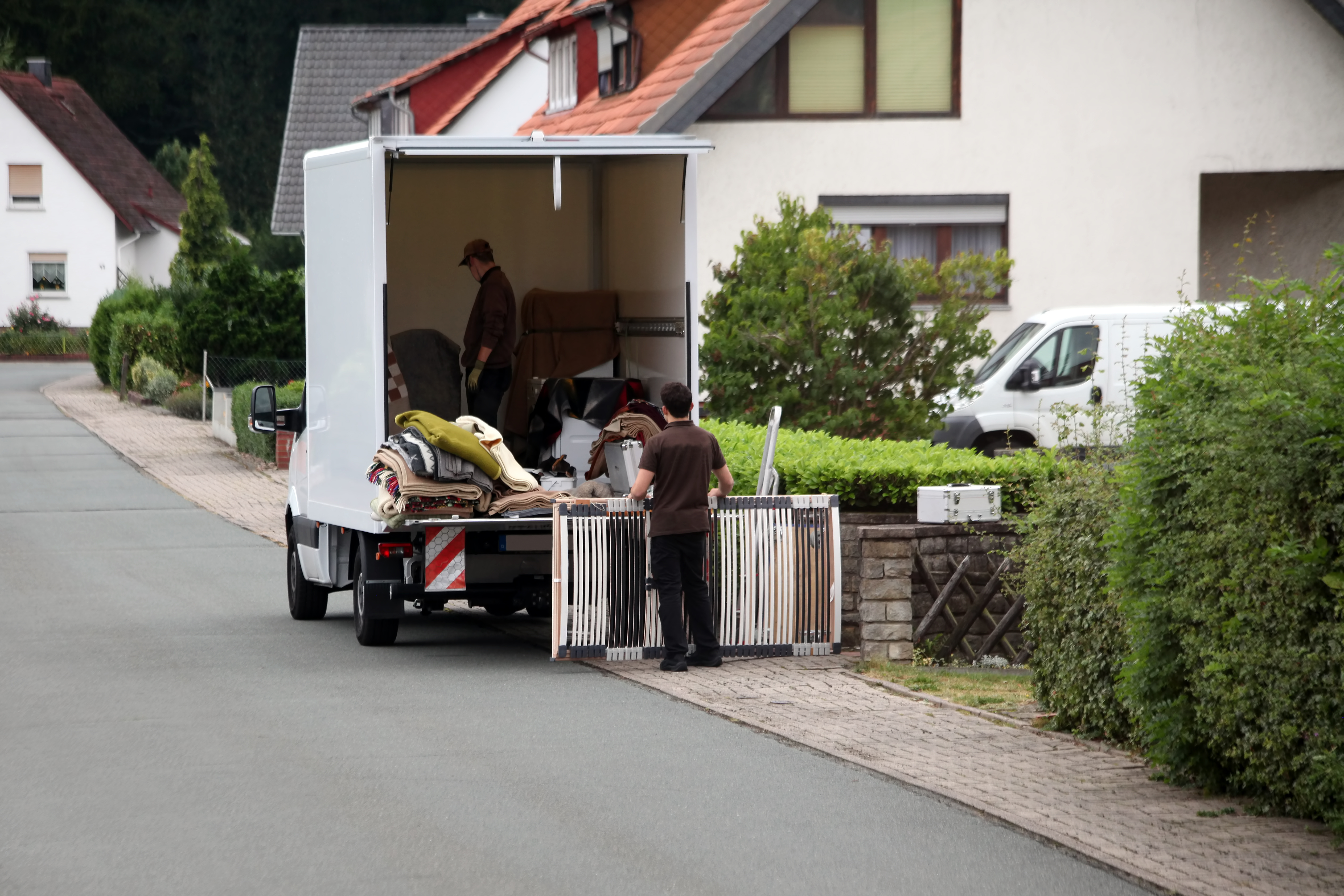 Haushalts- oder Wohnungsauflösung mit Möbeltransport – Umzugshelfer laden Möbel und Hausrat in ein Transportfahrzeug.